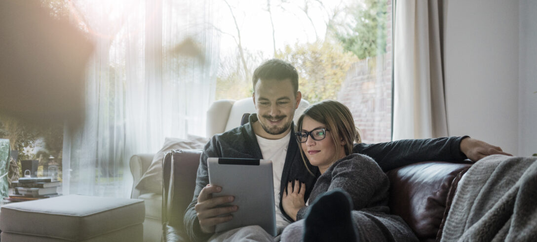 couple d'amoureux allongé sur le canapé en regardant un film sur la tablette