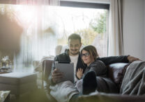 couple d'amoureux allongé sur le canapé en regardant un film sur la tablette