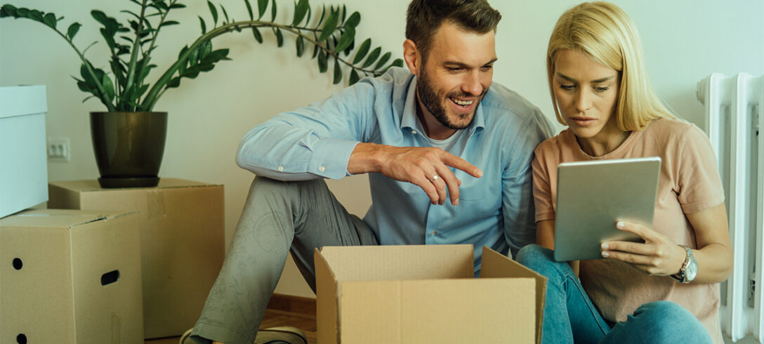 couple déménageant en faisant une pause. La femme a une tablette dans la main et l'homme la regarde