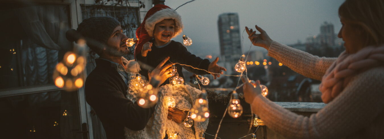 Jeune famille s'amusant ensemble sur la terrasse de leur appartement, décorant pour les vacances de Noël