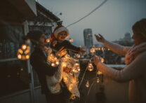 Jeune famille s'amusant ensemble sur la terrasse de leur appartement, décorant pour les vacances de Noël