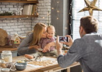 Famille avec un enfant faisant des biscuits pour les vacances de Noël, le père prend une photo pour un mémo