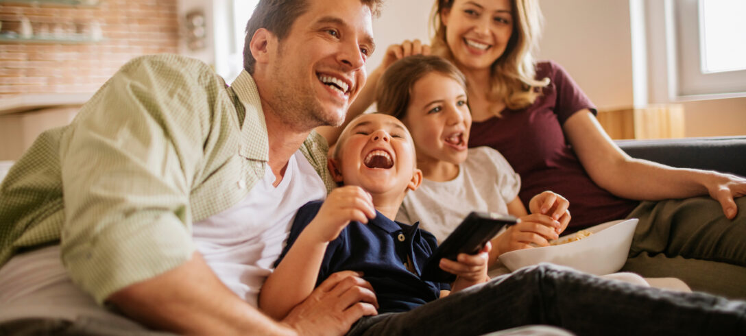 famille souriante regardant la télévision dans le salon