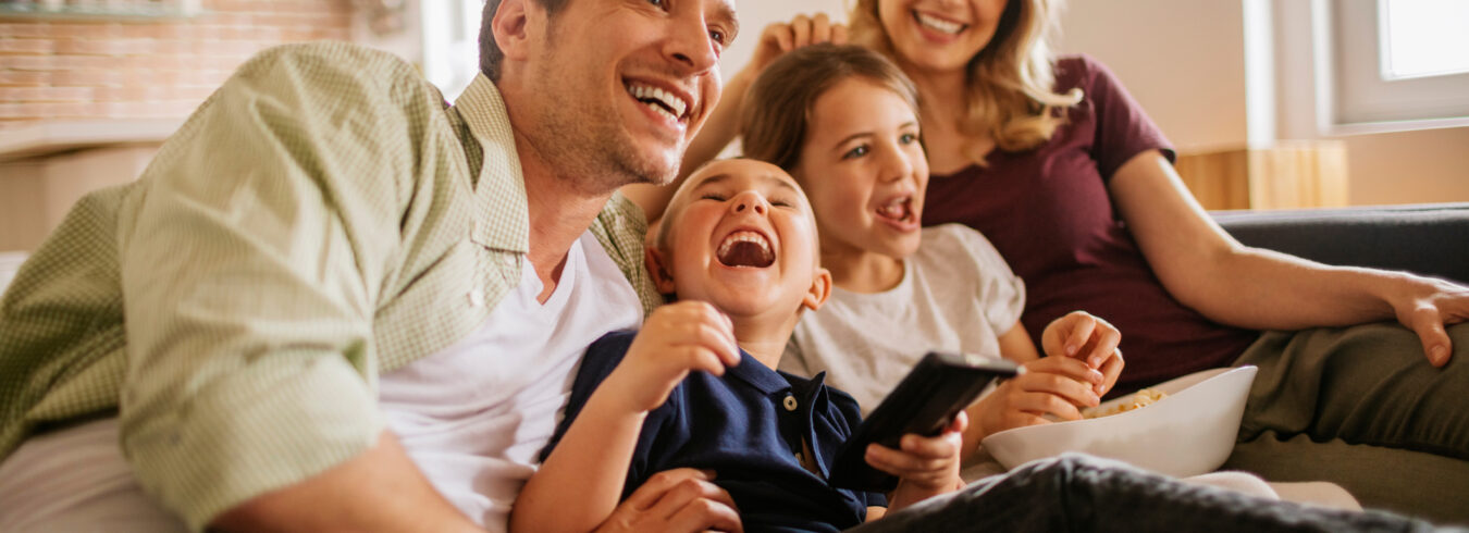 famille souriante regardant la télévision dans le salon
