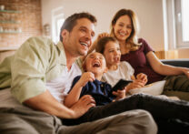 famille souriante regardant la télévision dans le salon