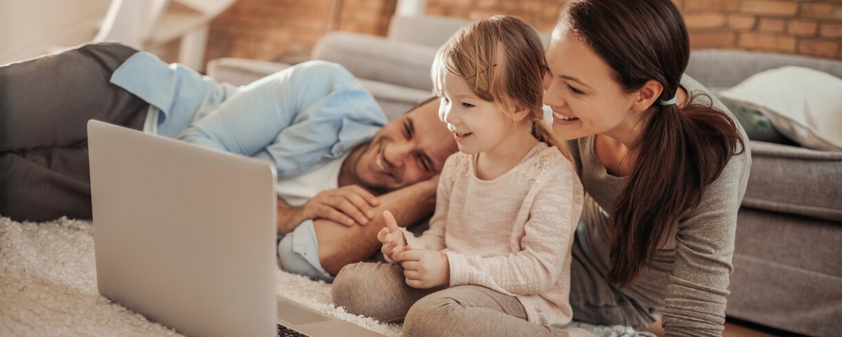 parents et fille regardant un film assis sur le sol du salon