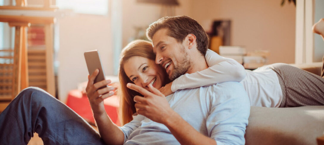 heureux couple d'amoureux regardant quelque chose sur leur téléphone portable
