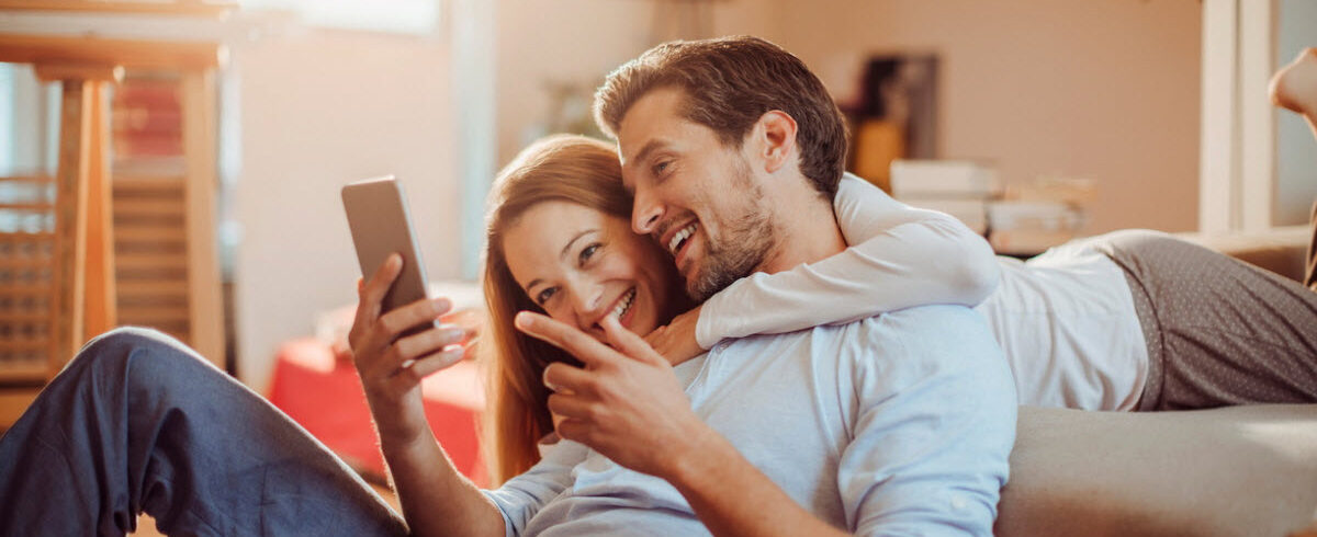 heureux couple d'amoureux regardant quelque chose sur leur téléphone portable