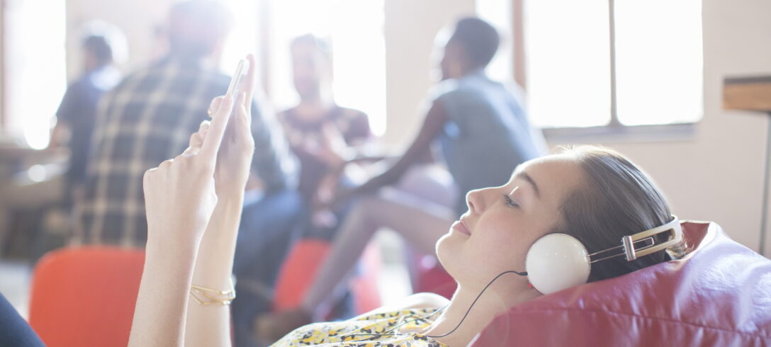 Femme d'affaires décontractée se relaxant avec un casque et une tablette numérique sur un fauteuil poire