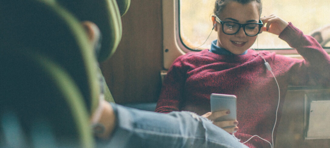 jeune femme assise avec les jambes tendues écoutant de la musique sur son téléphone portable avec un casque
