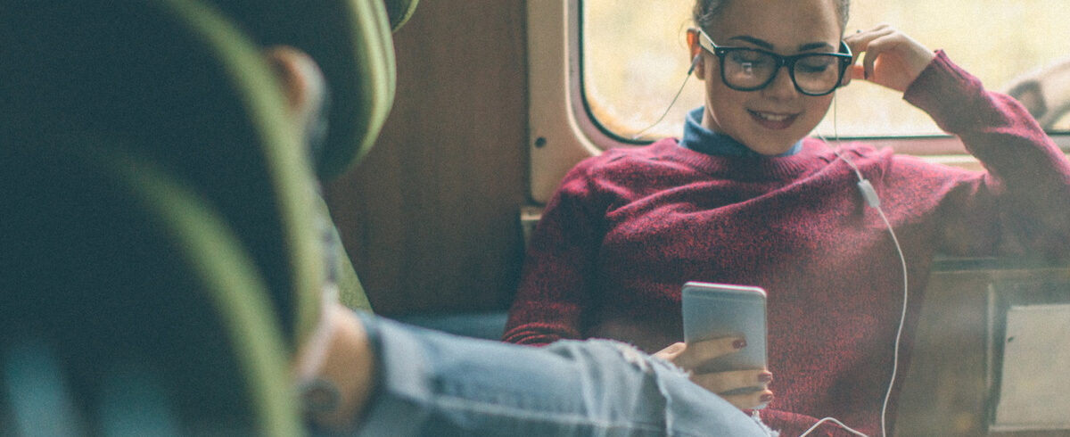 jeune femme assise avec les jambes tendues écoutant de la musique sur son téléphone portable avec un casque