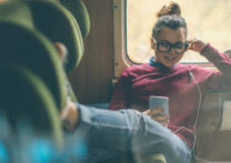 jeune femme assise avec les jambes tendues écoutant de la musique sur son téléphone portable avec un casque