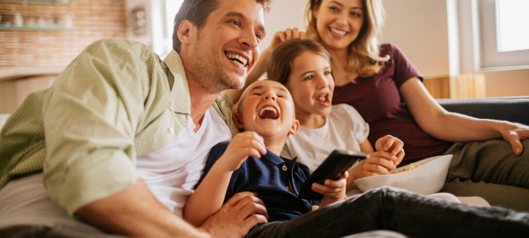 famille assise sur le canapé en regardant un film