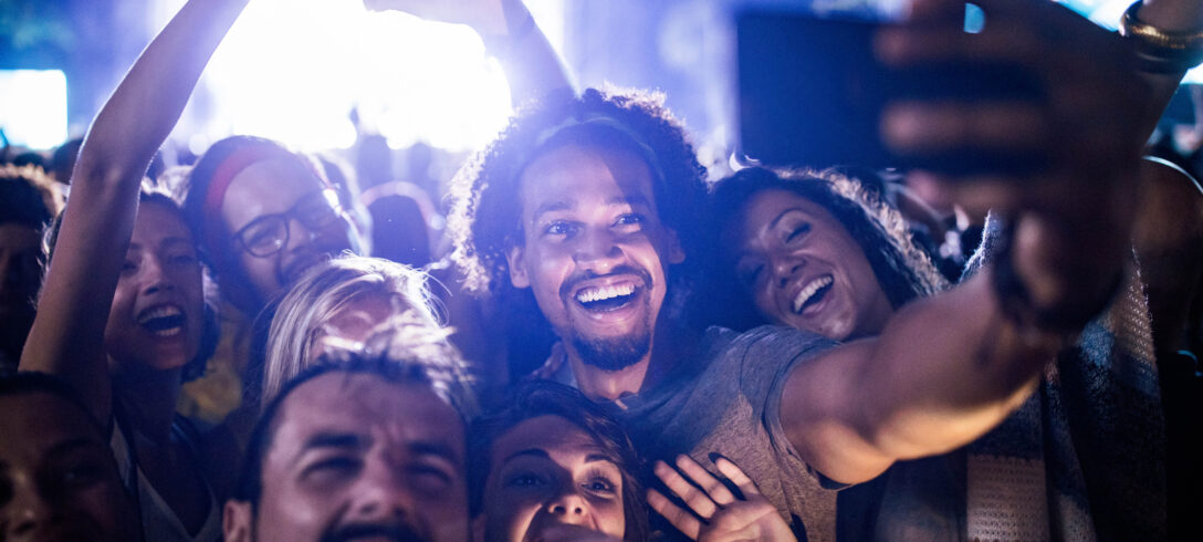 Grand groupe d'amis heureux s'amusant tout en prenant un selfie avec un téléphone portable lors d'un concert de musique.
