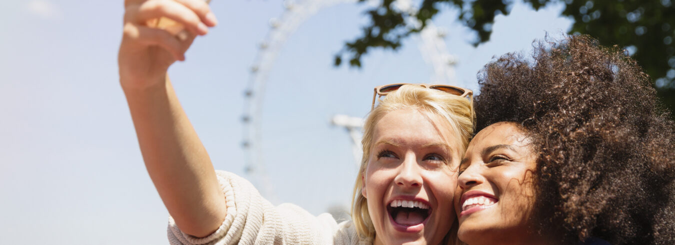 Amis prenant selfie avec London Eye en arrière-plan, Londres, Royaume-Uni