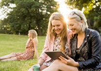 deux amies assises dans le jardin regardant une vidéo sur leur tablette