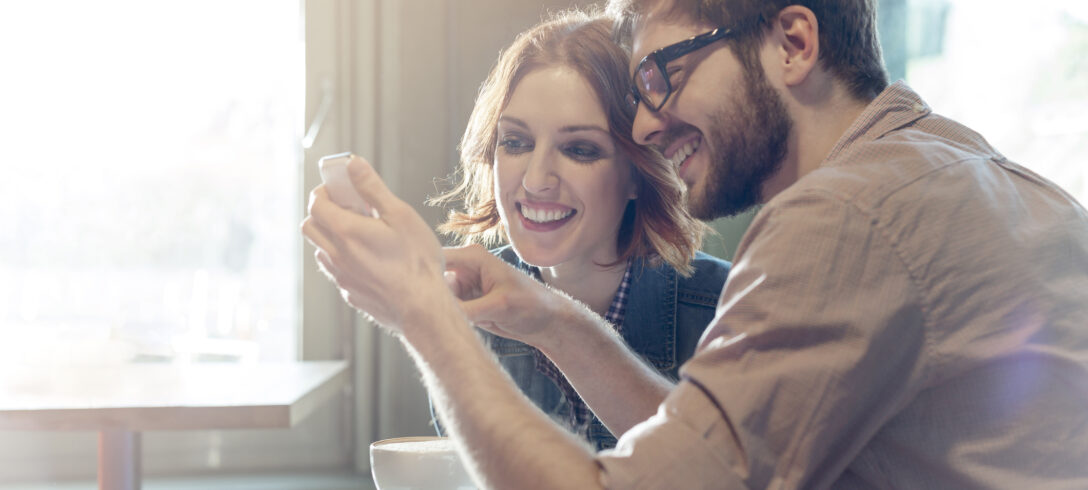 couple regardant une photo sur son téléphone portable en buvant du café