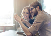 couple regardant une photo sur son téléphone portable en buvant du café