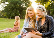 trois amis dans un grand jardin, l'un d'eux montre quelque chose sur le téléphone portable à l'autre