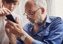 petit-fils apprenant à son grand-père à utiliser le téléphone portable