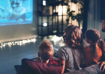famille regardant un film projeté sur le mur à la maison