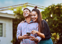 couple d'amoureux riant en regardant son téléphone portable