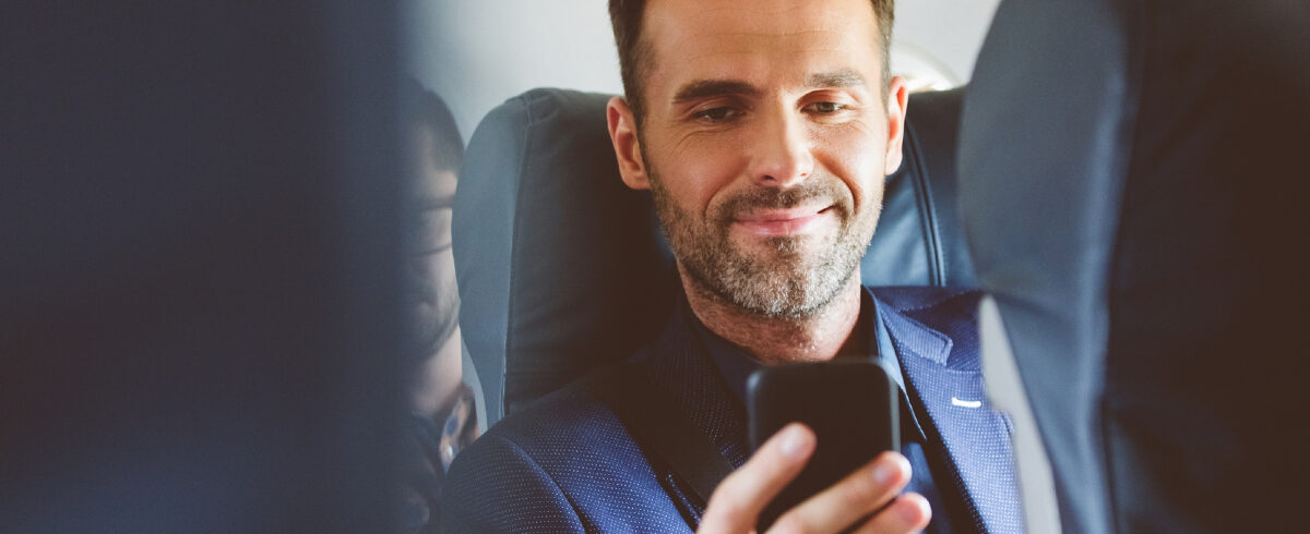 homme d'affaires sur un vol regardant son téléphone portable