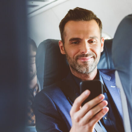 homme d'affaires sur un vol regardant son téléphone portable