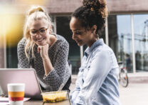 deux femmes parlent affaires en regardant un ordinateur portable