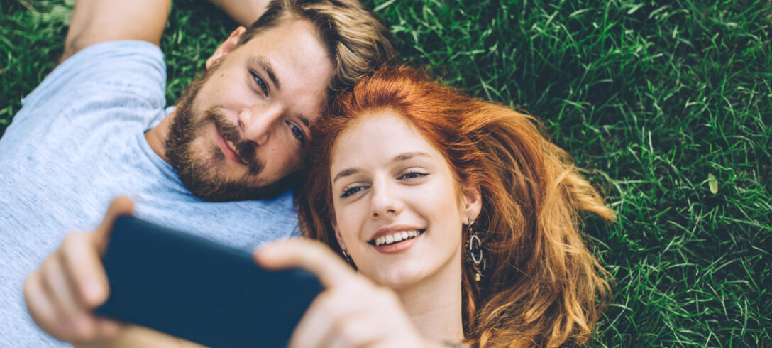 couple allongé sur l'herbe prenant un selfie