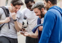 Groupe de jeunes hommes sportifs urbains s'amusant avec un téléphone intelligent au parc de la ville