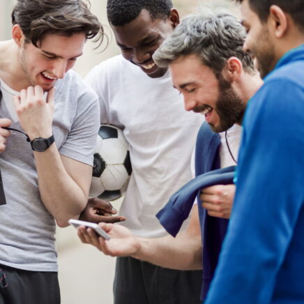 Groupe de jeunes hommes sportifs urbains s'amusant avec un téléphone intelligent au parc de la ville