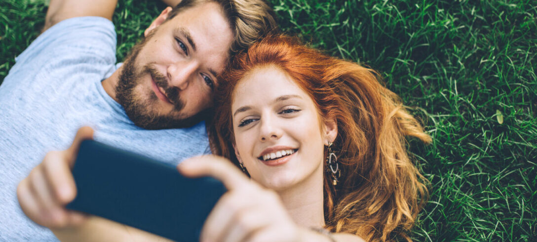 couple allongé sur l'herbe prenant un selfie