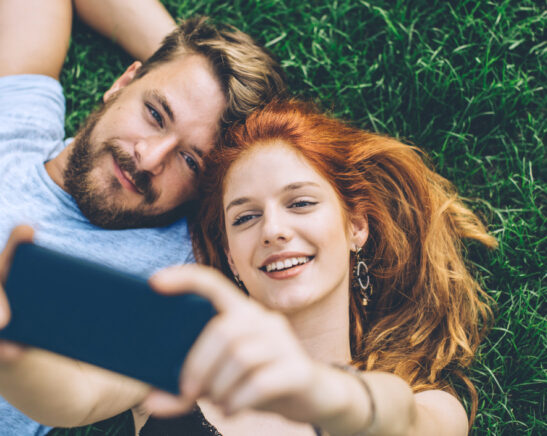 couple allongé sur l'herbe prenant un selfie