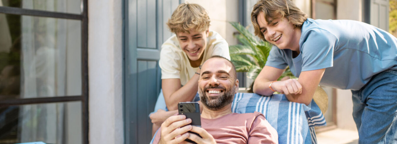 Un papa montre son téléphone à ses deux fils