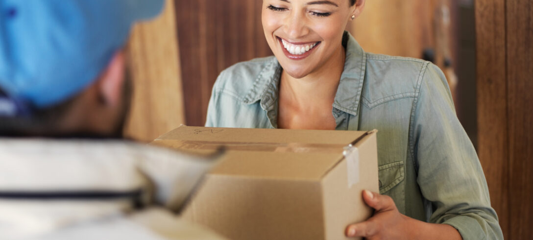 femme souriante recevant un colis à sa porte