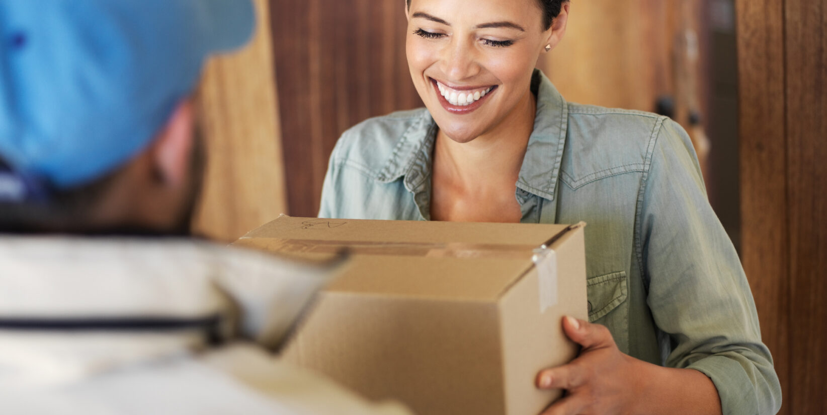 femme souriante recevant un colis à sa porte