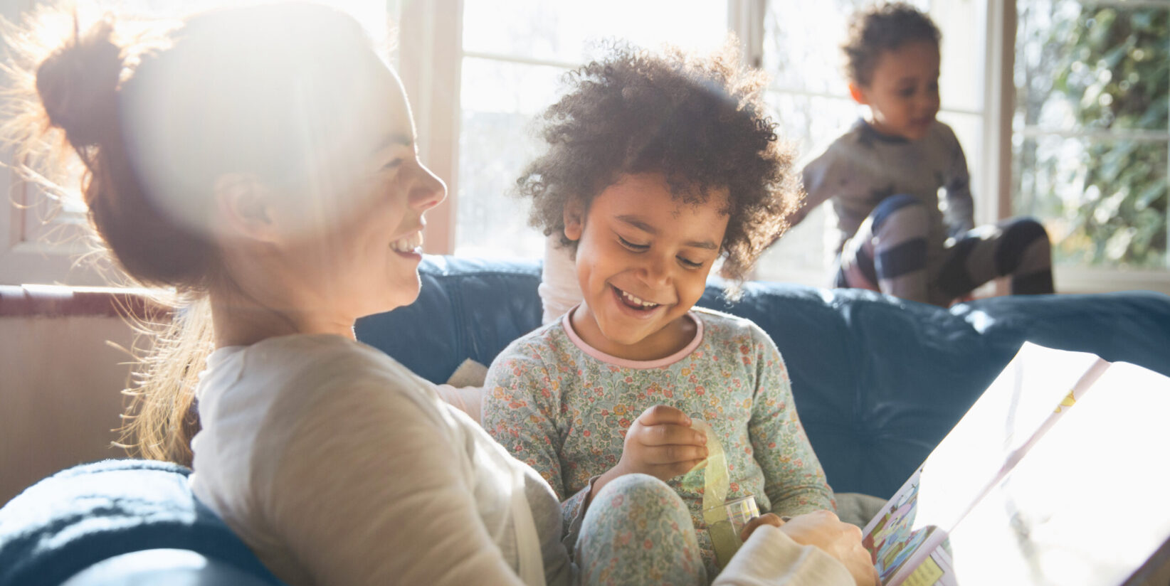 mère racontant une histoire à ses enfants assis sur le canapé en souriant
