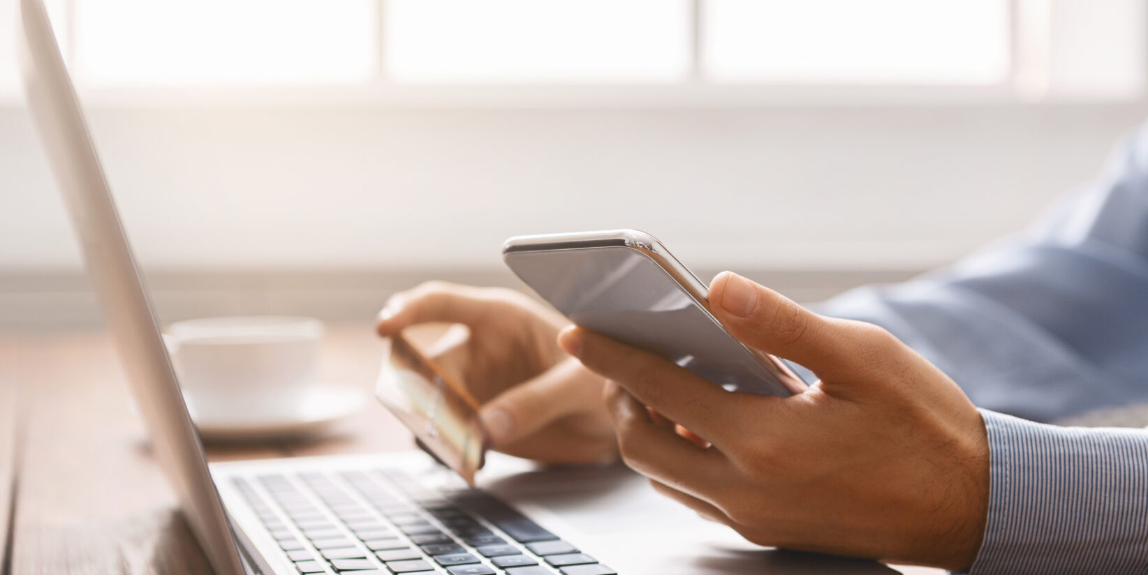 Homme d'affaires méconnaissable faisant des achats en ligne à l'aide d'un smartphone et d'une carte de crédit.