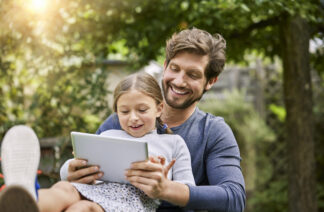 Happy father and daughter using tablet together in garden