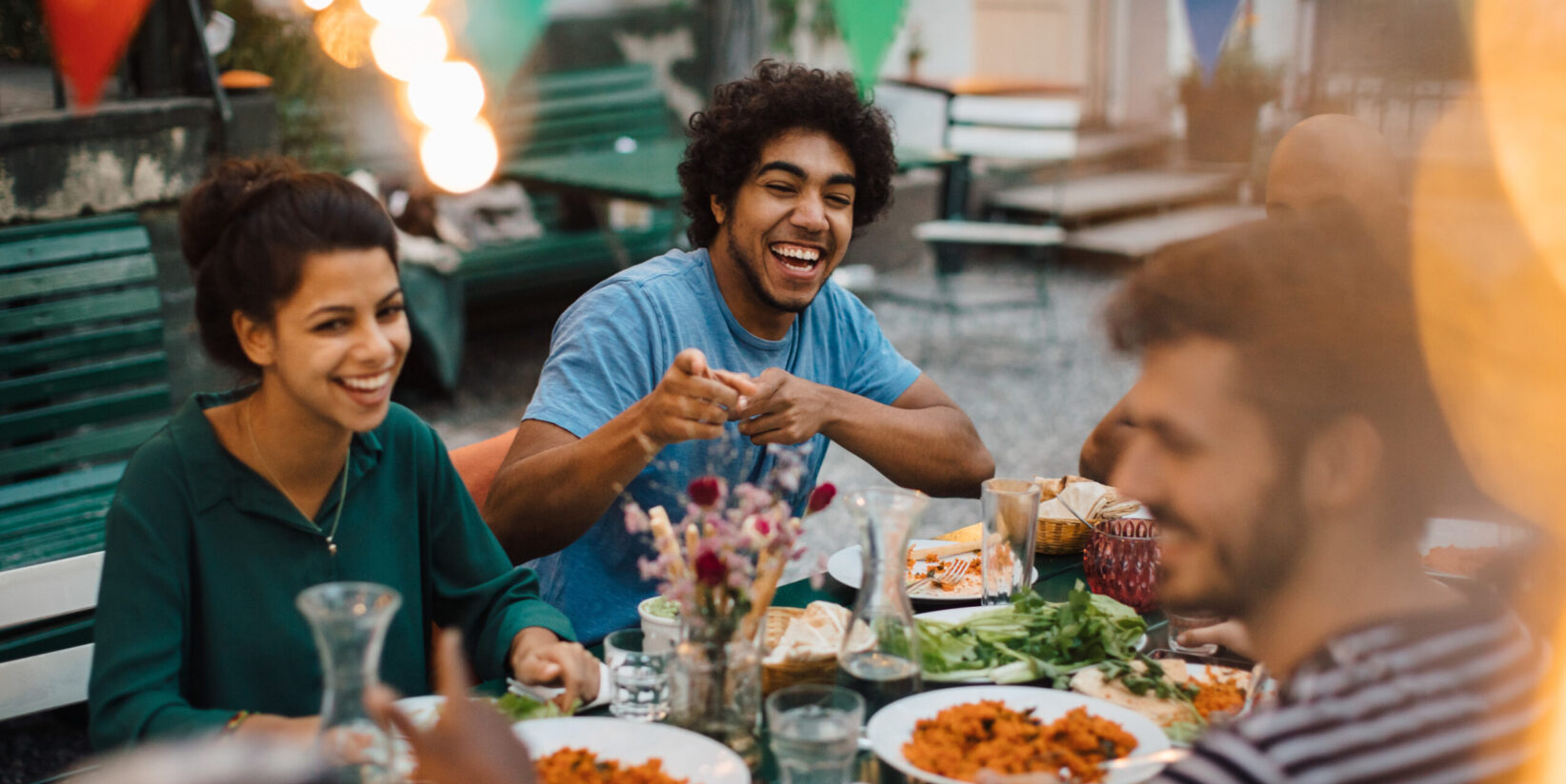 Joyeux amis masculins et féminins appréciant pendant le dîner dans la cour