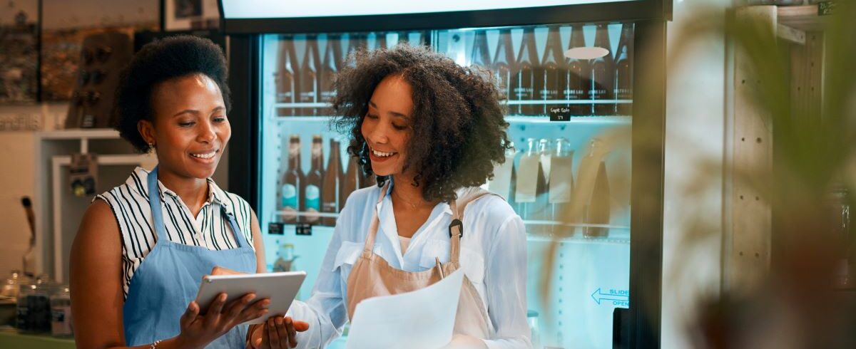 2 femmes africaines regardant les résultats du magasin à l'aide d'une tablette tout en se parlant