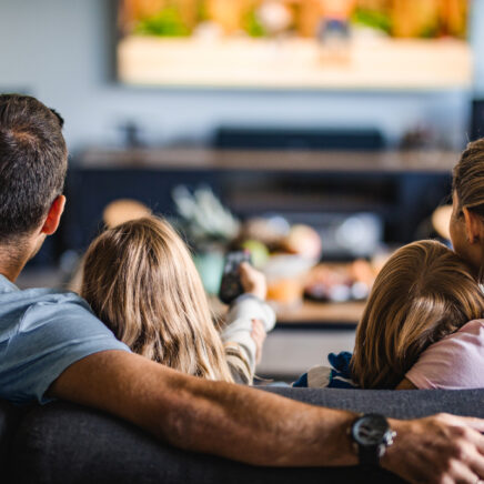 famille assise sur le canapé en regardant la télévision