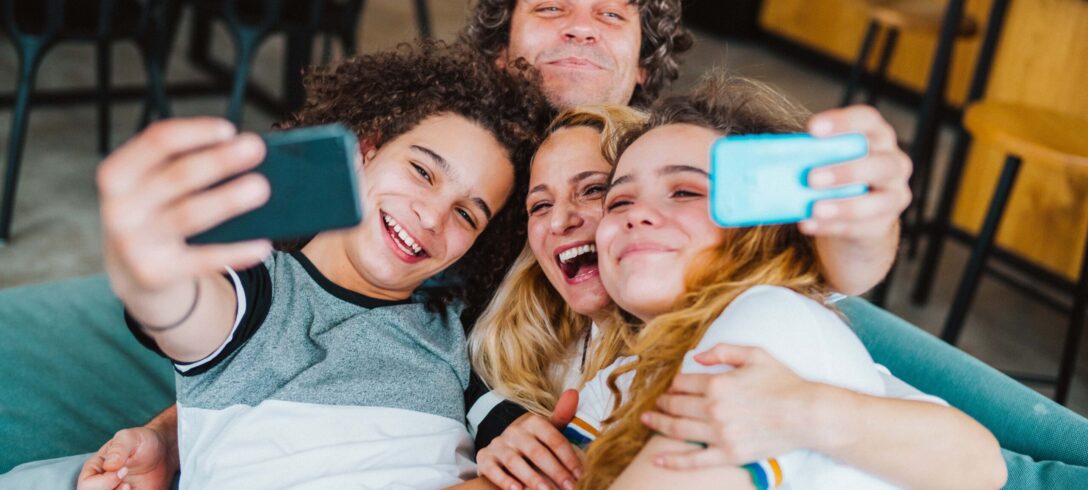 Joyeuse famille assise sur le canapé et prenant un selfie