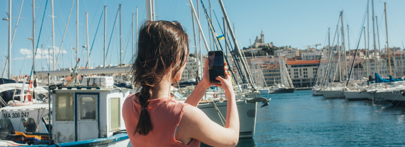 jeune homme prenant une photo de bateaux à la marina