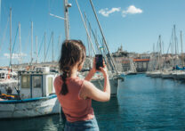 jeune homme prenant une photo de bateaux à la marina