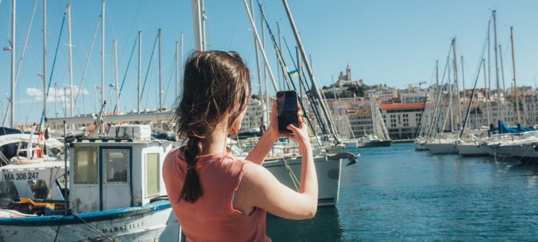 jeune homme prenant une photo de bateaux à la marina