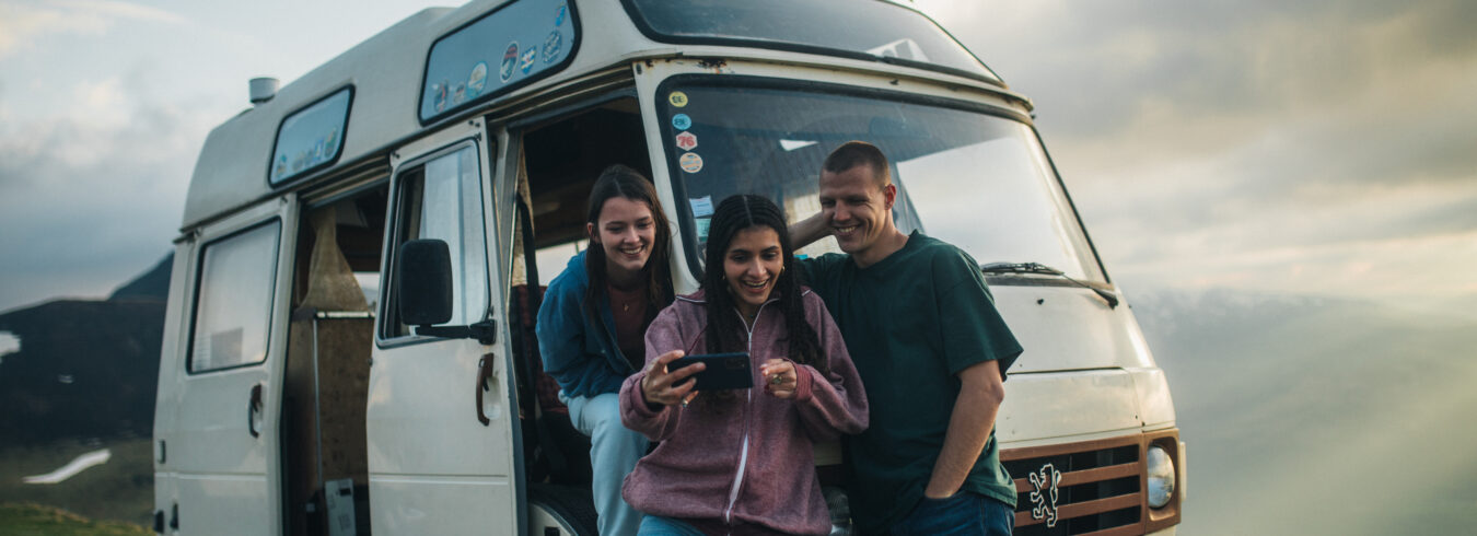 3 amis en road trip regardant les photos qu'ils ont prises sur leurs téléphones portables