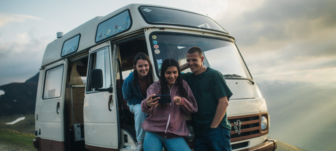 3 amis en road trip regardant les photos qu'ils ont prises sur leurs téléphones portables