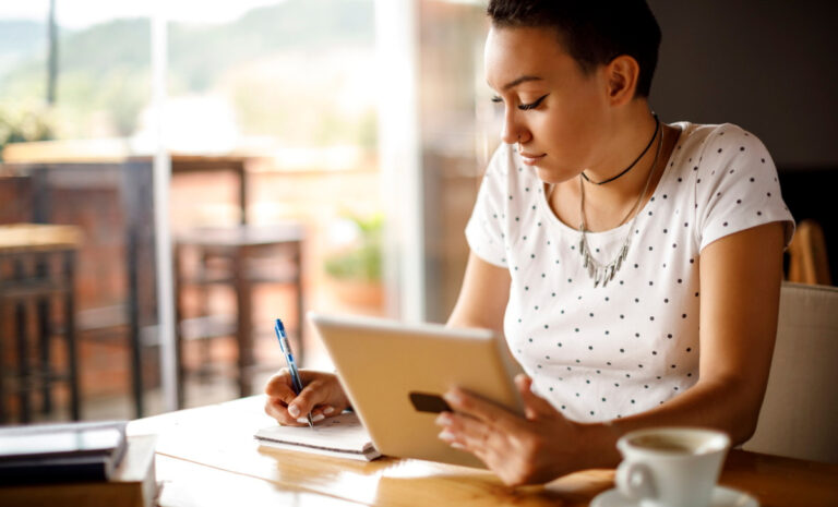 femme assise dans un café travaillant sur sa tablette